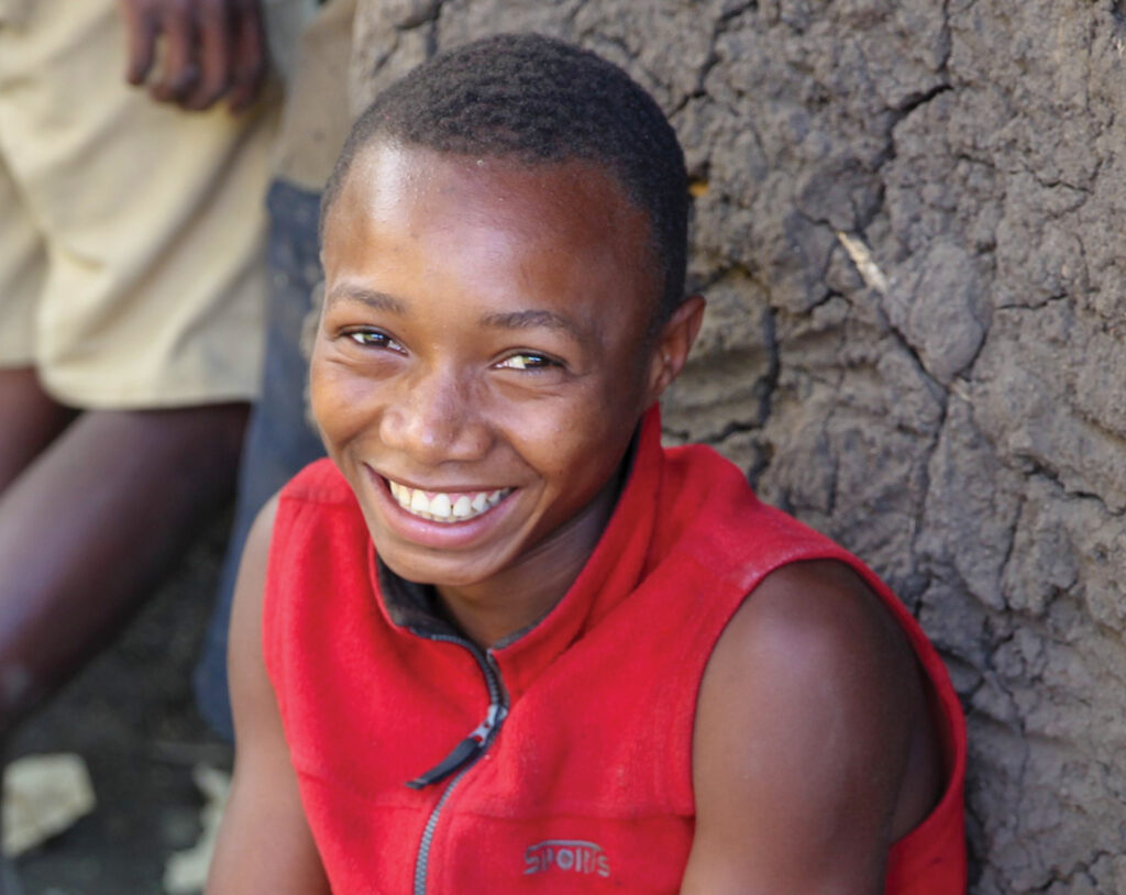 Boy sitting outside of his house smiling 