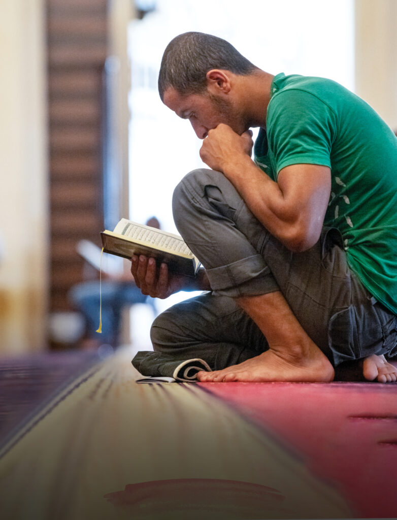 man kneels on the ground as he reads 