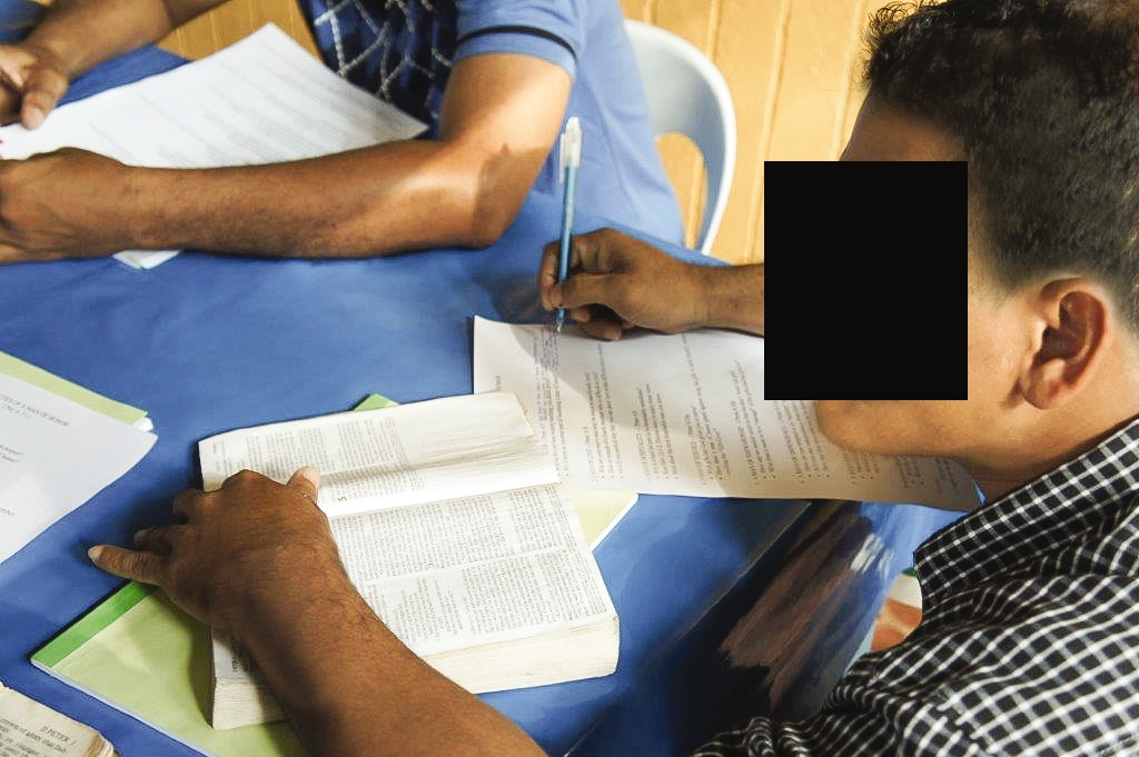 man sits at a table to read and study the bible 