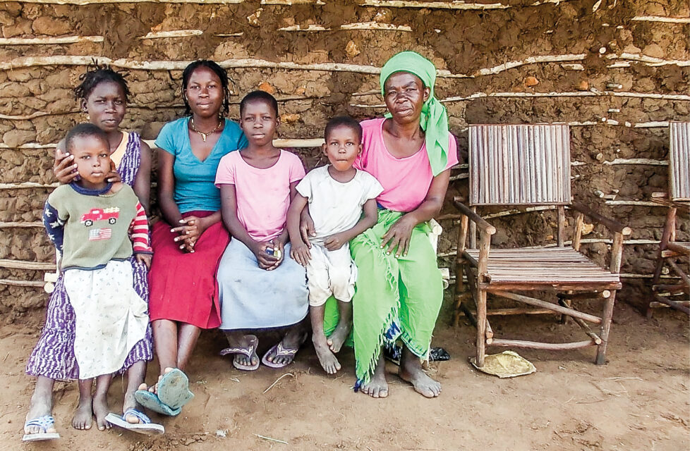 A woman and children sitting in front of their house