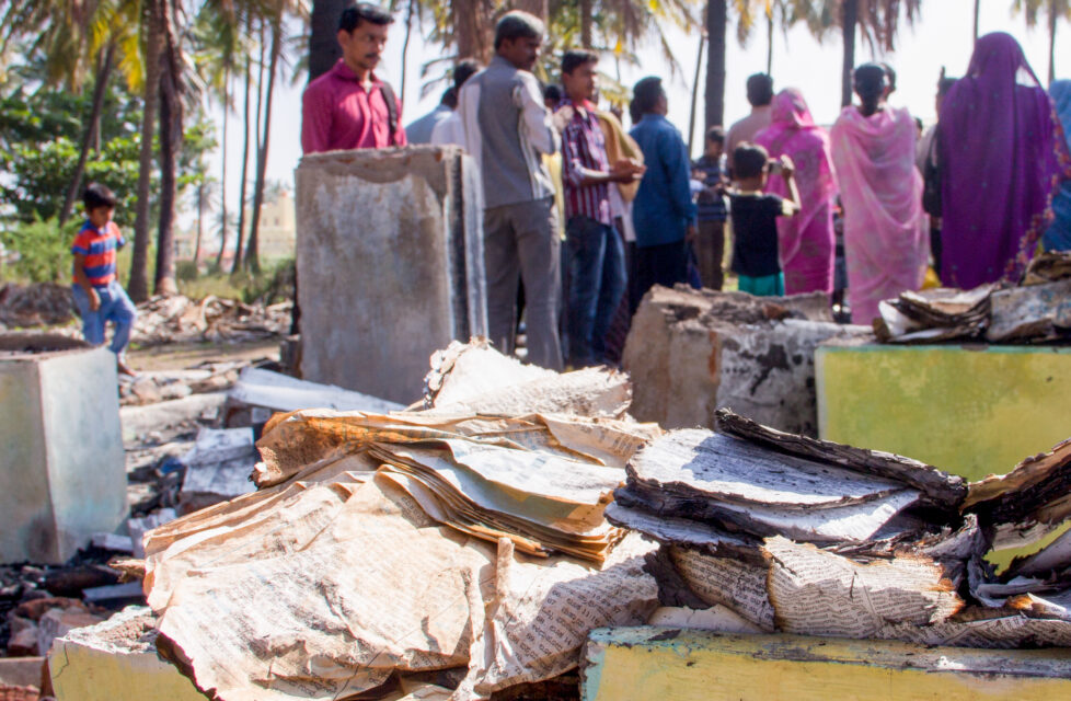 A group of people gathered looking at a burned Bible