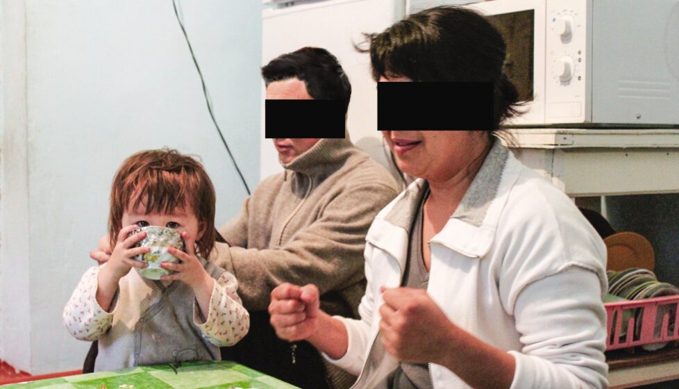 a husband and wife sit with their daughter at their kitchen table